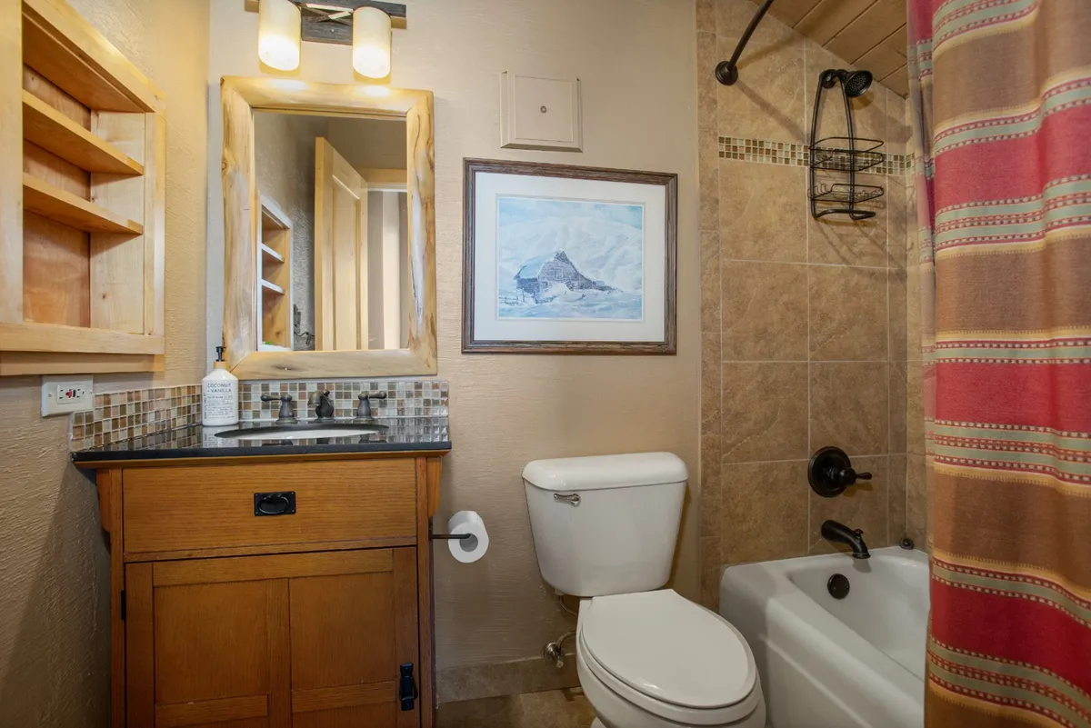 A modern bathroom featuring a vanity with a mirror, framed artwork, and a sleek shower. The ambiance is calming and serene, suggesting a spa-like atmosphere for relaxation and personal care.