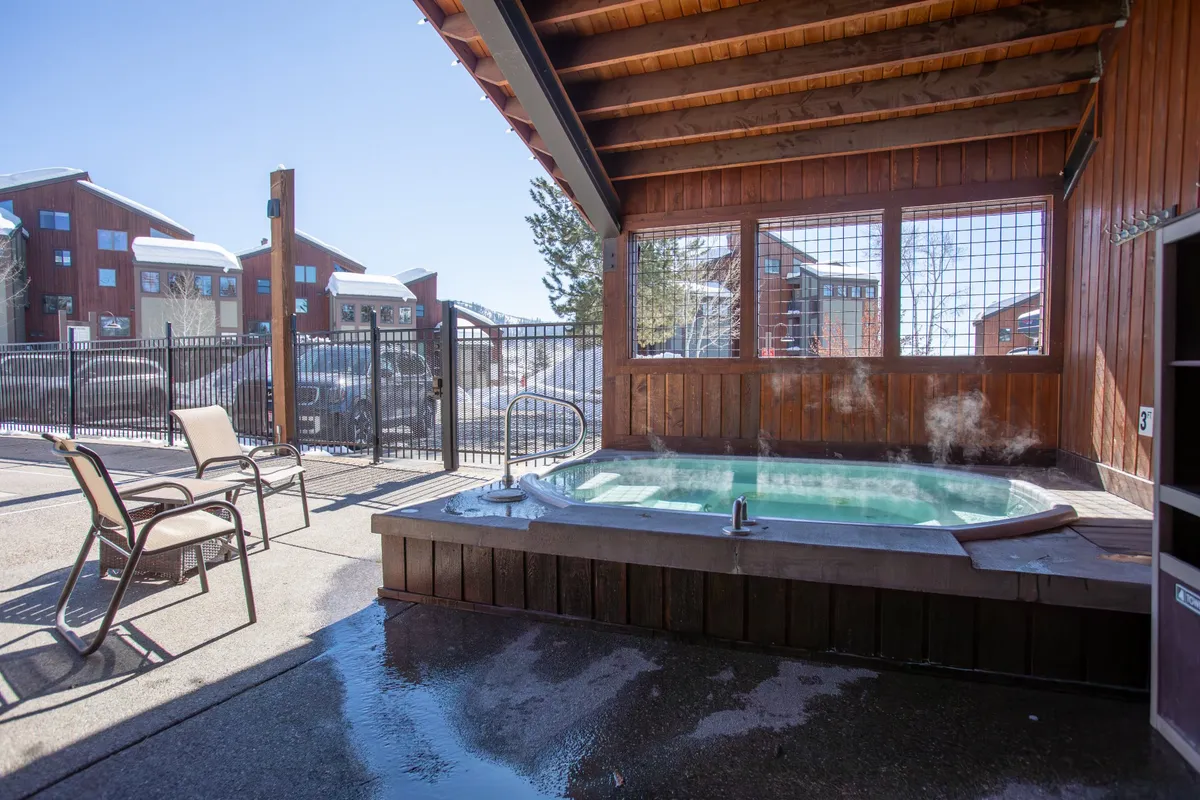 An inviting outdoor hot tub area framed by wooden beams and surrounded by outdoor seating. The space exudes relaxation and social opportunity, suggesting a soothing après-ski retreat where guests can unwind after exhilarating mountain adventures.